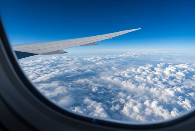 機内の窓から見える主翼と雲の上の景色